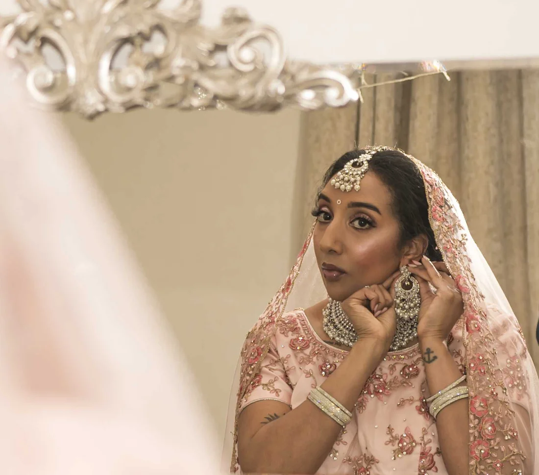 An Asian bride in a pink embroidered dupatta and bridal jewellery